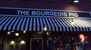 The sign and striped awning of the Bourgeois Pig, a cocktail bar on Massachusetts Street.