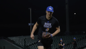 A KU Baseball player wears his baseball glove while running on the field.