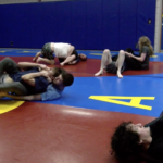 Members of the KU Jiu Jitsu club ground fighting on the floor of the Martial Arts room in the Ambler Student Recreation Center.