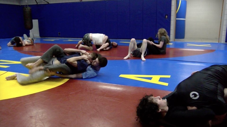 Members of the KU Jiu Jitsu club ground fighting on the floor of the Martial Arts room in the Ambler Student Recreation Center.