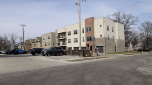 An apartment complex and a telephone pole in the background with a parking lot in the foreground