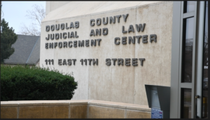 A building with signage on the wall reads "Douglas County Judicial and Law Enforcement Center, 111 East 11th Street"