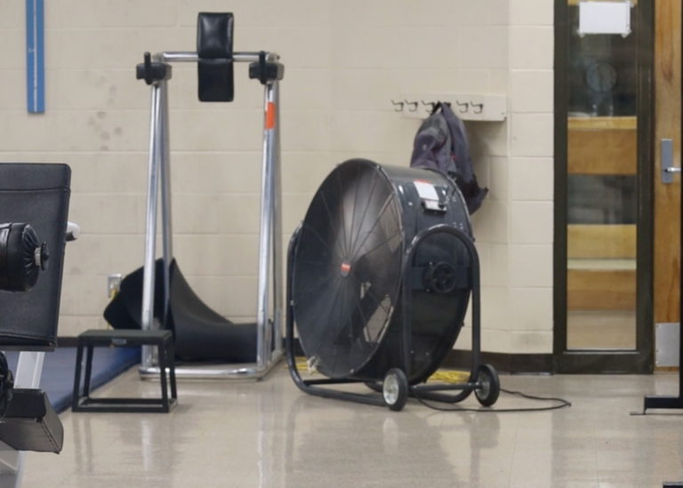 A big box fan sits in a room among other equipment